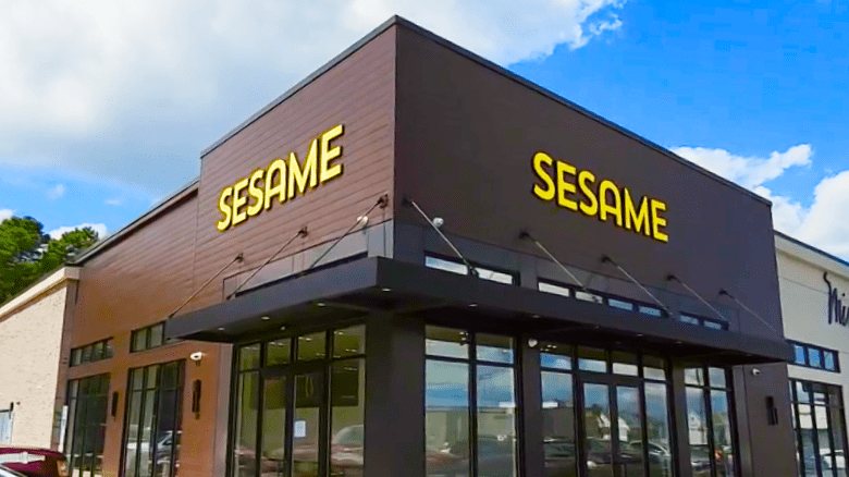 The Sesame storefront with yellow lettering on a dark brown facade above a canopy and glass doors